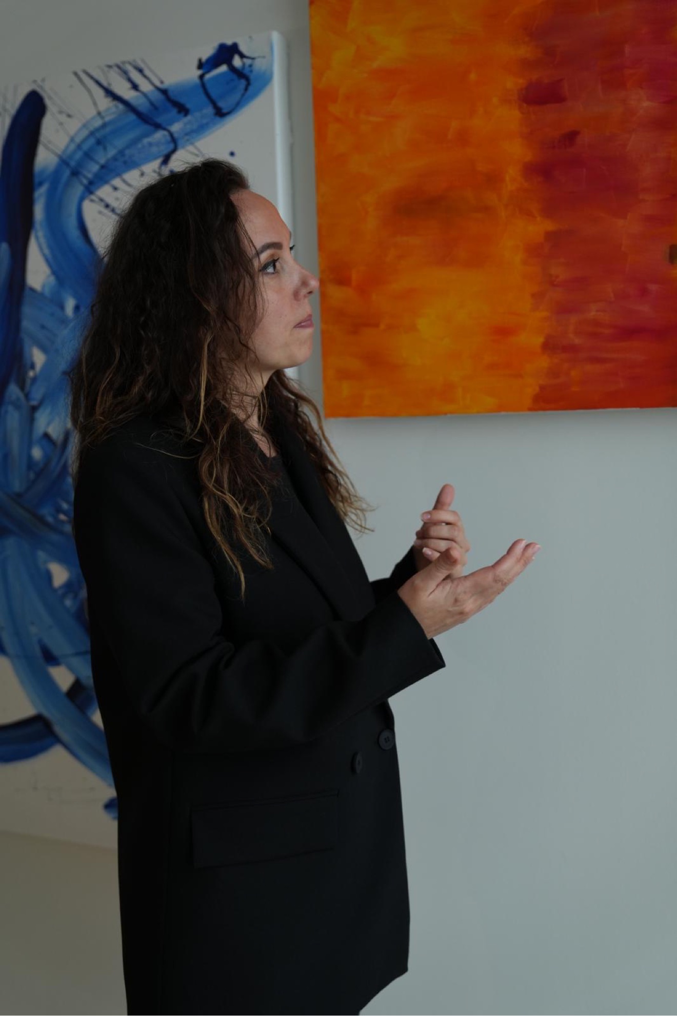 Zhanna beside her blue and orange energy paintings